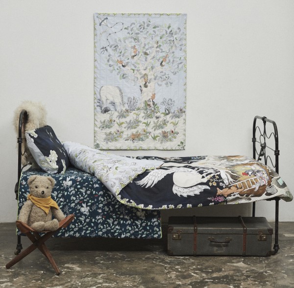 Forivor's Enchanted Forest Bedding shown with the Enchanted Forest Quilted Blanket hanging on the wall and the Hidden Foxes and Tumbling Pegasus Blanket on the Bed. 