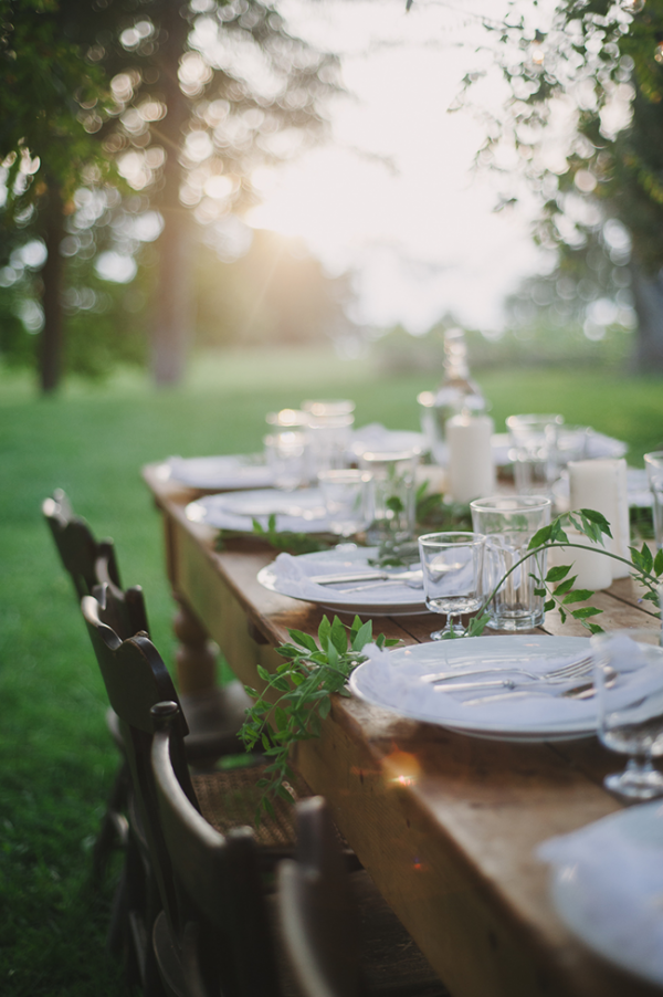 Keep it restrained and chic with plain white dinnerware and candles on a rustic timber table. Just add trailing greenery to bring it to life. via A Daily Something.