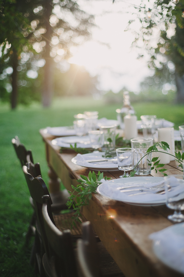 Keep it restrained and chic with plain white dinnerware and candles on a rustic timber table. Just add trailing greenery to bring it to life. via A Daily Something.  